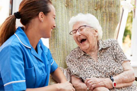 Photograph of a care worker laughing with an elderly lady.