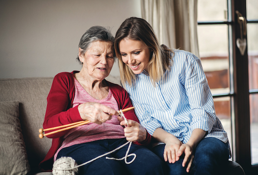 Resident showing her knitting to a carer